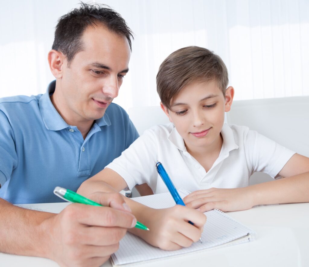 A father helping his son with schoolwork at the kitchen table