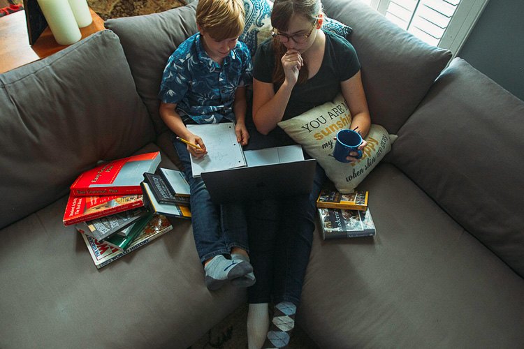 A mother and her son reading together on the couch, surrounded by books
